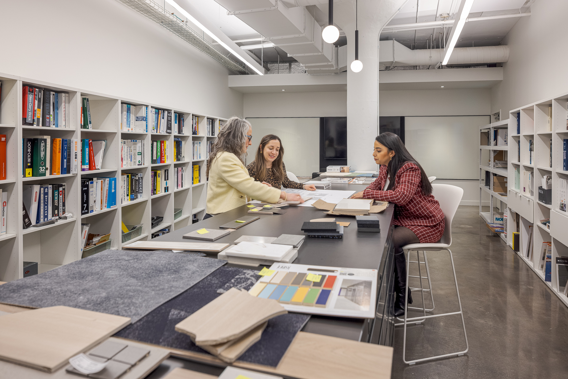 Trois membres de l'équipe de design d'intérieur travaillant ensemble dans la matériauthèque des bureaux de GKC Architecture & Design